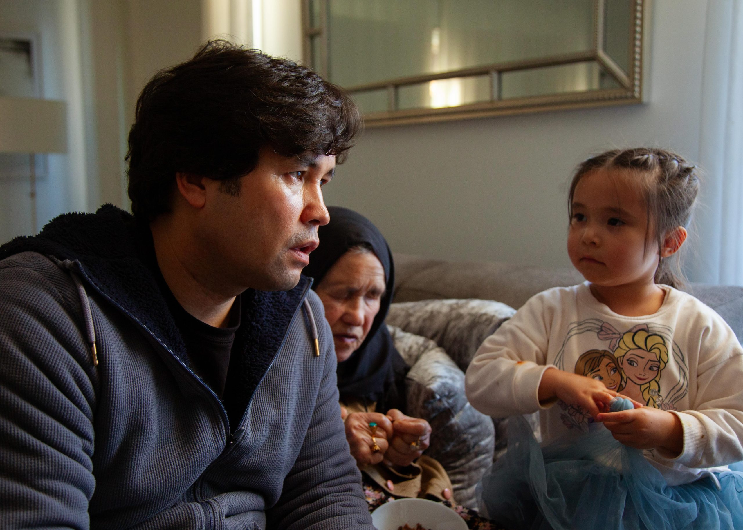 Film director & photojournalist Barat Ali Batoor, sits in his loungeroom, with his mother Hawa and his daughter.