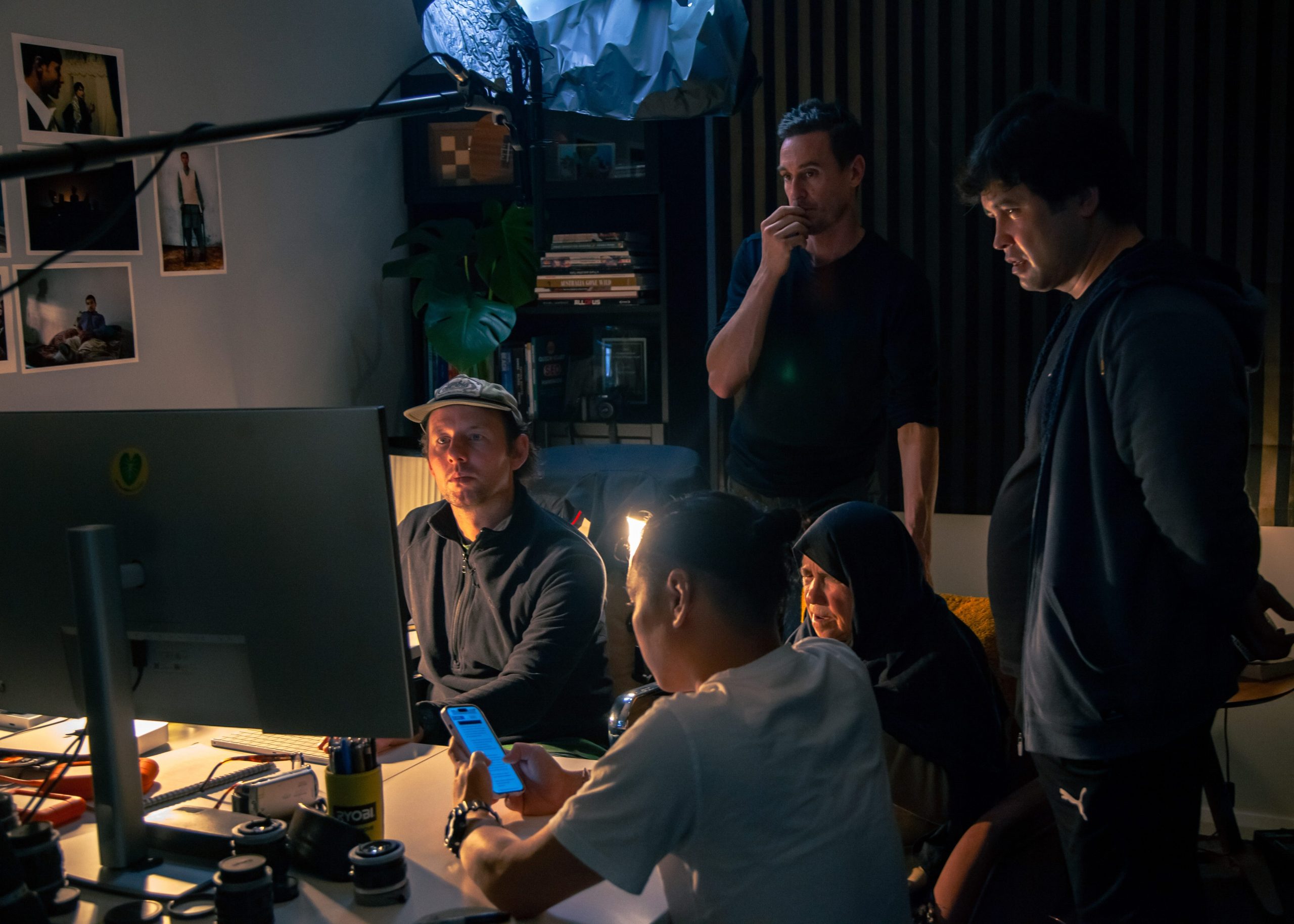 The My Refugee Journey film team view a monitor in a darkened room.